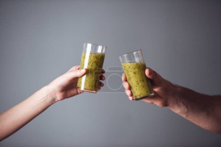 Photo for Cropped image of young sports people holding nutritious cocktails, on gray background - Royalty Free Image