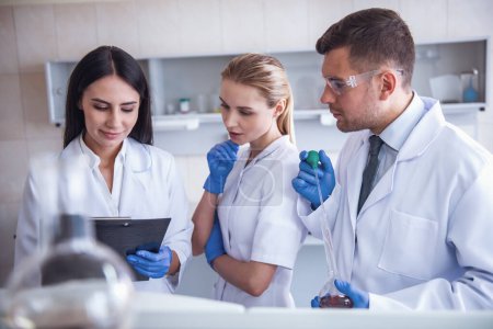 Photo for Beautiful medical doctors in gloves are discussing test results while working at the lab - Royalty Free Image