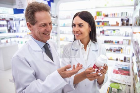 Photo for Beautiful pharmacists are discussing medication and smiling while working in pharmacy - Royalty Free Image