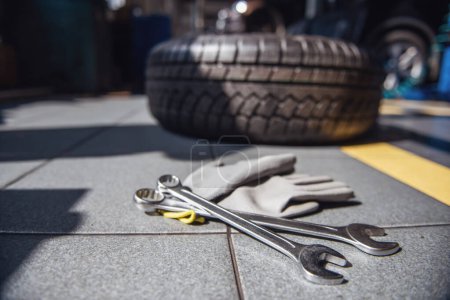 Photo for At the auto service. Auto mechanic's equipment. Tools, gloves and tire in the background - Royalty Free Image