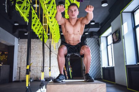 Foto de Guapo joven deportista muscular está trabajando con una caja de ejercicios en el gimnasio - Imagen libre de derechos