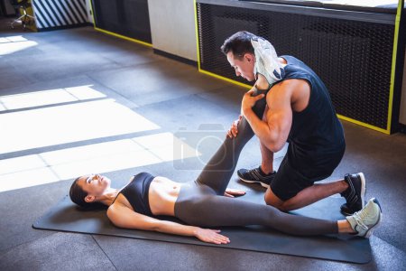 Photo for Beautiful young sports couple is stretching after workout in gym - Royalty Free Image