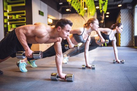 Foto de Hermosos jóvenes deportistas están haciendo ejercicio con pesas en el gimnasio - Imagen libre de derechos