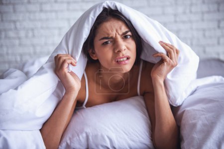 Photo for Smiling woman under a duvet in her bedroom - Royalty Free Image