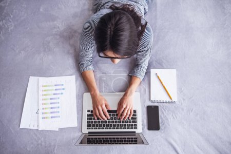 Photo for Home office. Successful young beautiful woman sitting on a bed working on a laptop. top view - Royalty Free Image