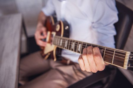 Foto de Imagen recortada del joven empresario tocando la guitarra en su oficina durante el descanso - Imagen libre de derechos