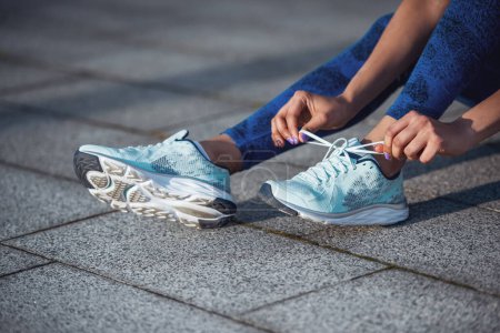 Foto de Imagen recortada de hermosa chica en ropa deportiva zapatos de correr de cordones durante la carrera de la mañana - Imagen libre de derechos