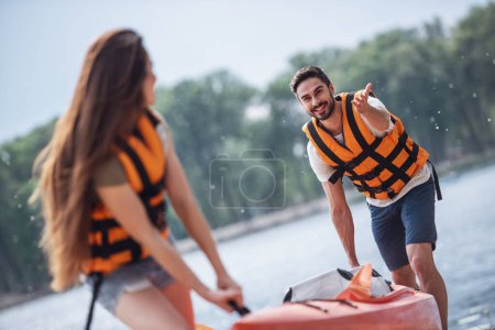 Photo for Happy young couple are pulling a kayak on the beach after sailing - Royalty Free Image
