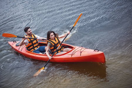 Téléchargez les photos : Joyeux jeune couple en gilet de mer navigue en kayak - en image libre de droit