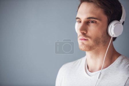 Foto de Hombre joven guapo en ropa casual y auriculares, sobre fondo gris - Imagen libre de derechos