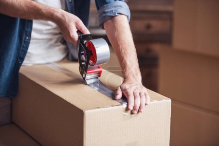 Photo for Cropped image of guy packing cardboard boxes while moving into new apartment - Royalty Free Image