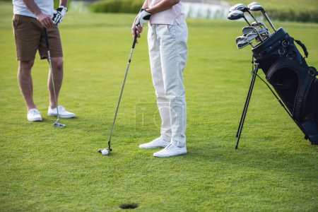 Téléchargez les photos : Image recadrée de personnes jouant au golf, un trou de golf au premier plan - en image libre de droit
