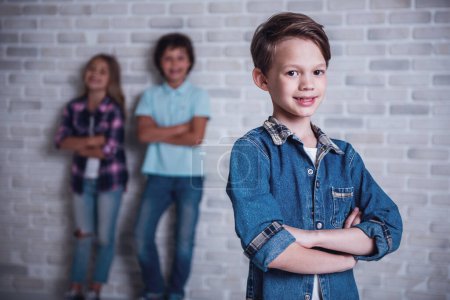 Photo for Cute kids are looking at camera and smiling, on white brick wall background. One boy in the foreground - Royalty Free Image