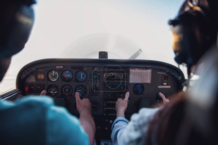 Téléchargez les photos : Vue arrière de l'intérieur de l'avion, couple dans les casques d'aviation est prêt à voler - en image libre de droit