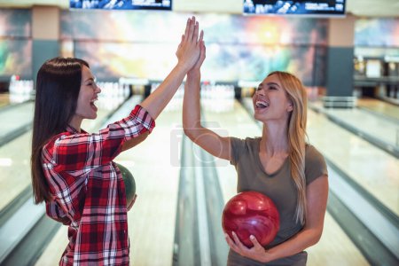 Téléchargez les photos : Belles filles tiennent des boules de bowling, donnant haute cinq et souriant prêt à jouer - en image libre de droit