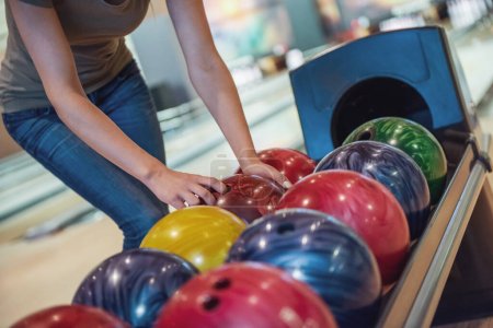 Téléchargez les photos : Image recadrée d'une jolie fille choisissant une boule de bowling prête à jouer - en image libre de droit