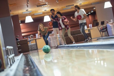 Photo for Happy young friends are having fun while playing bowling together - Royalty Free Image