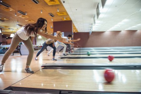 Téléchargez les photos : Heureux jeunes amis s'amusent tout en jouant au bowling ensemble - en image libre de droit