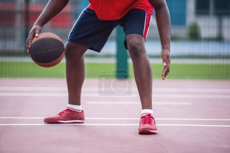 Téléchargez les photos : Image recadrée d'un beau joueur de basket-ball jouant sur le terrain de basket à l'extérieur - en image libre de droit