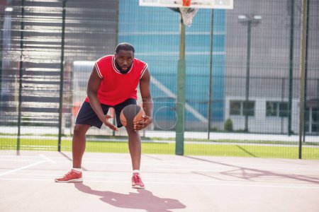 Téléchargez les photos : Beau joueur de basket joue sur le terrain de basket en plein air - en image libre de droit