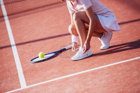 Foto de Imagen recortada de la chica que ata a sus entrenadores mientras juega al tenis en la cancha al aire libre - Imagen libre de derechos