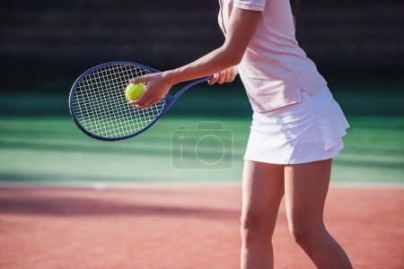Photo for Cropped image of girl holding tennis racket while playing tennis on court outdoors - Royalty Free Image