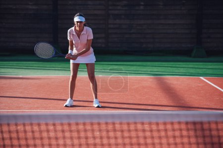 Photo for Beautiful young girl is holding tennis racket while playing tennis on court outdoors - Royalty Free Image