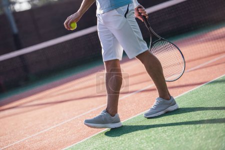 Téléchargez les photos : Image recadrée d'un bel homme tenant une raquette de tennis tout en jouant au tennis sur le terrain à l'extérieur - en image libre de droit