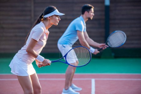 Foto de Hermosa pareja joven están jugando al tenis como un equipo en la cancha de tenis al aire libre - Imagen libre de derechos