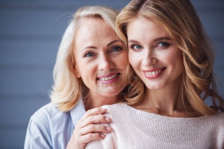 Photo for Beautiful senior mom and her adult daughter are hugging, looking at camera and smiling - Royalty Free Image