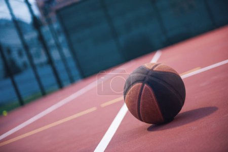 Téléchargez les photos : Basket de couleur foncée couché sur le terrain de basket à l'extérieur - en image libre de droit