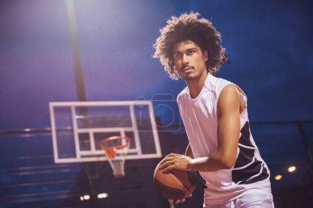 Photo for Attractive basketball player is playing basketball outdoors in the evening - Royalty Free Image