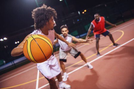 Téléchargez les photos : Beaux gars jouent au basket en plein air la nuit - en image libre de droit