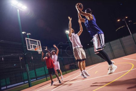 Téléchargez les photos : Beaux gars jouent au basket en plein air la nuit - en image libre de droit