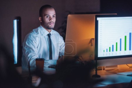Photo for Handsome Afro American businessman in classic suit is using a computer while working in office late in the evening - Royalty Free Image