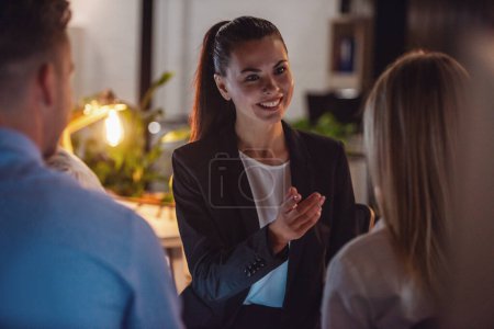 Photo for Successful business people are sitting in circle and discussing affairs while working in office late at night - Royalty Free Image