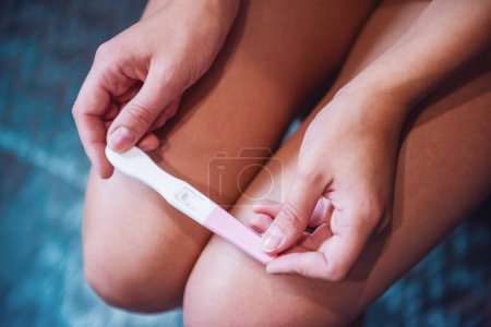 Téléchargez les photos : Image recadrée d'une femme tenant un test de grossesse à genoux - en image libre de droit