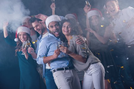 Téléchargez les photos : Des gens heureux buvant du champagne et s'amusant tout en célébrant le Nouvel An, sur fond sombre et fumé. Beau couple au premier plan - en image libre de droit