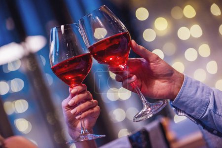Téléchargez les photos : Image recadrée de couple cliquetis verres de vin ensemble tout en ayant une date dans un restaurant - en image libre de droit