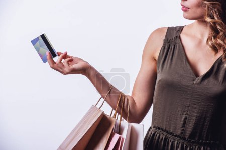 Foto de Imagen recortada de mujer joven en vestido con una tarjeta de crédito y bolsas de compras, sobre fondo claro - Imagen libre de derechos