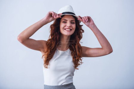 Photo for Portrait of a happy young girl with a hat on a white background smiling at the camera - Royalty Free Image