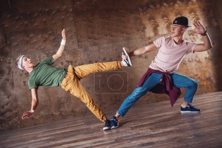 Téléchargez les photos : Les jeunes hommes cassent la danse sur le fond du mur, exécutant des tours - en image libre de droit