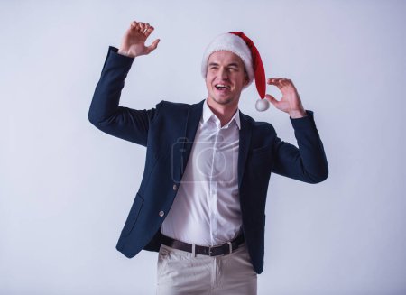 Foto de Chico guapo en traje y sombrero de Santa está levantando las manos y riendo, aislado en blanco - Imagen libre de derechos