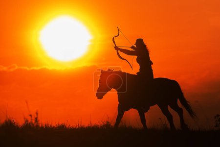 silhouette d'un cavalier avec un cheval et un arc contre le soleil