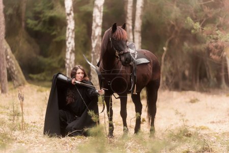 noir habillé femme dans historique agenouillé par un cheval et pointant un arc