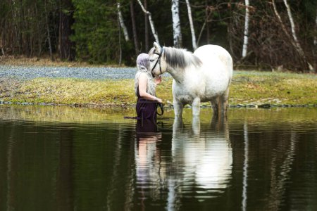 Foto de Mujer con el pelo blanco es el agua con el caballo blanco - Imagen libre de derechos