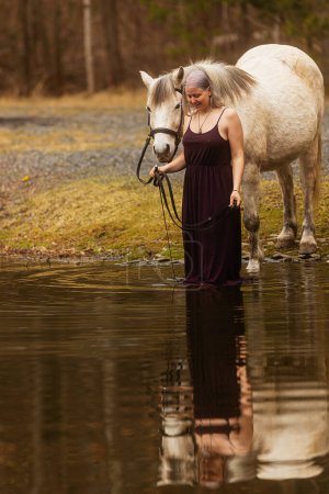 Foto de Mujer con el pelo blanco al aguacon caballo blanco - Imagen libre de derechos