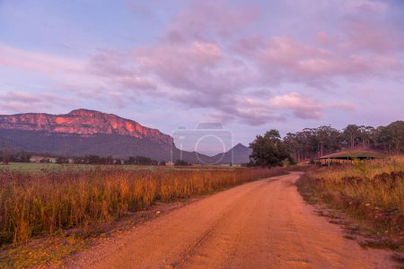 Photo for Morning sunlight htting the top of the ridges and their sheer cliff faces where the landscape is bathed in soft orange and red tones - Royalty Free Image