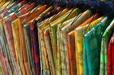  View of Indian woman traditional dress sarees in display, on hangers in a shop                                           