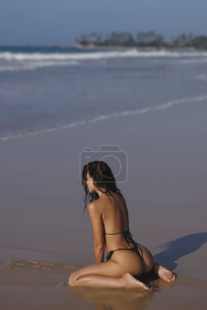 Foto de Summer is the perfect time to be sexy. Fashion shot of a gorgeous young woman in black bikini on the beach outdoors. High quality photo - Imagen libre de derechos